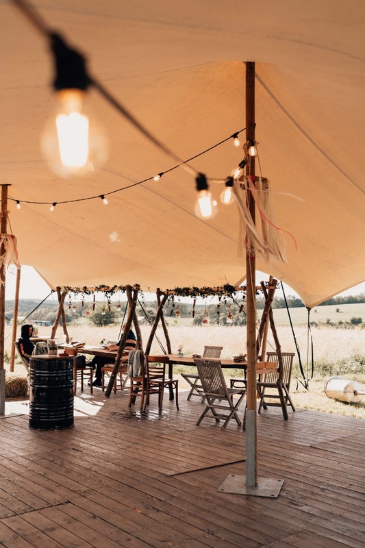 Table de mariage dressée sous une tente stretch, guirlandes lumineuses