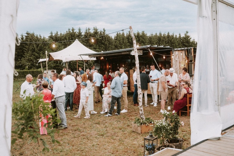 Invités d’un mariage réunis près de la tente, dans le jardin