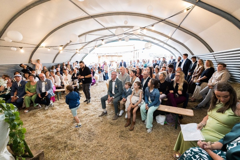 Invités réunis pour une cérémonie de mariage sous un hangar décoré