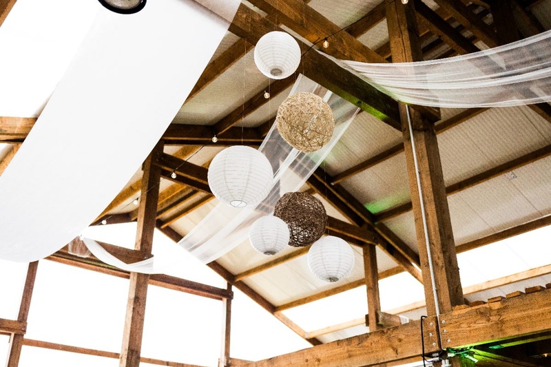 Décoration de mariage : lanternes et voilages sous une charpente en bois