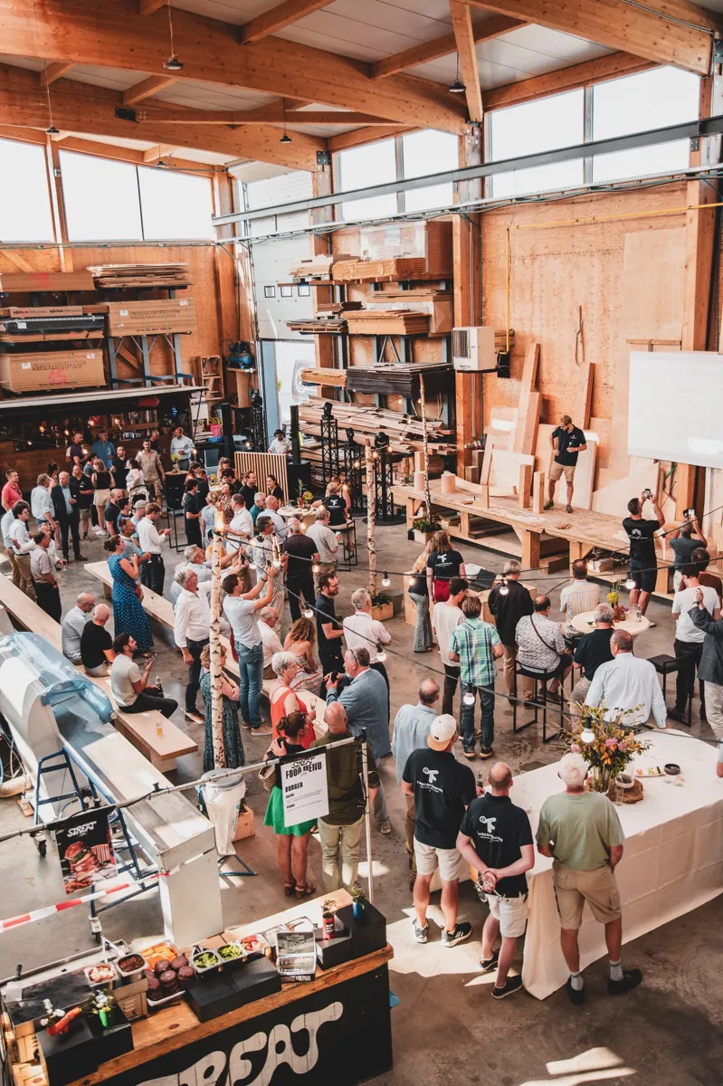 Invités réunis dans un atelier bois pour une inauguration