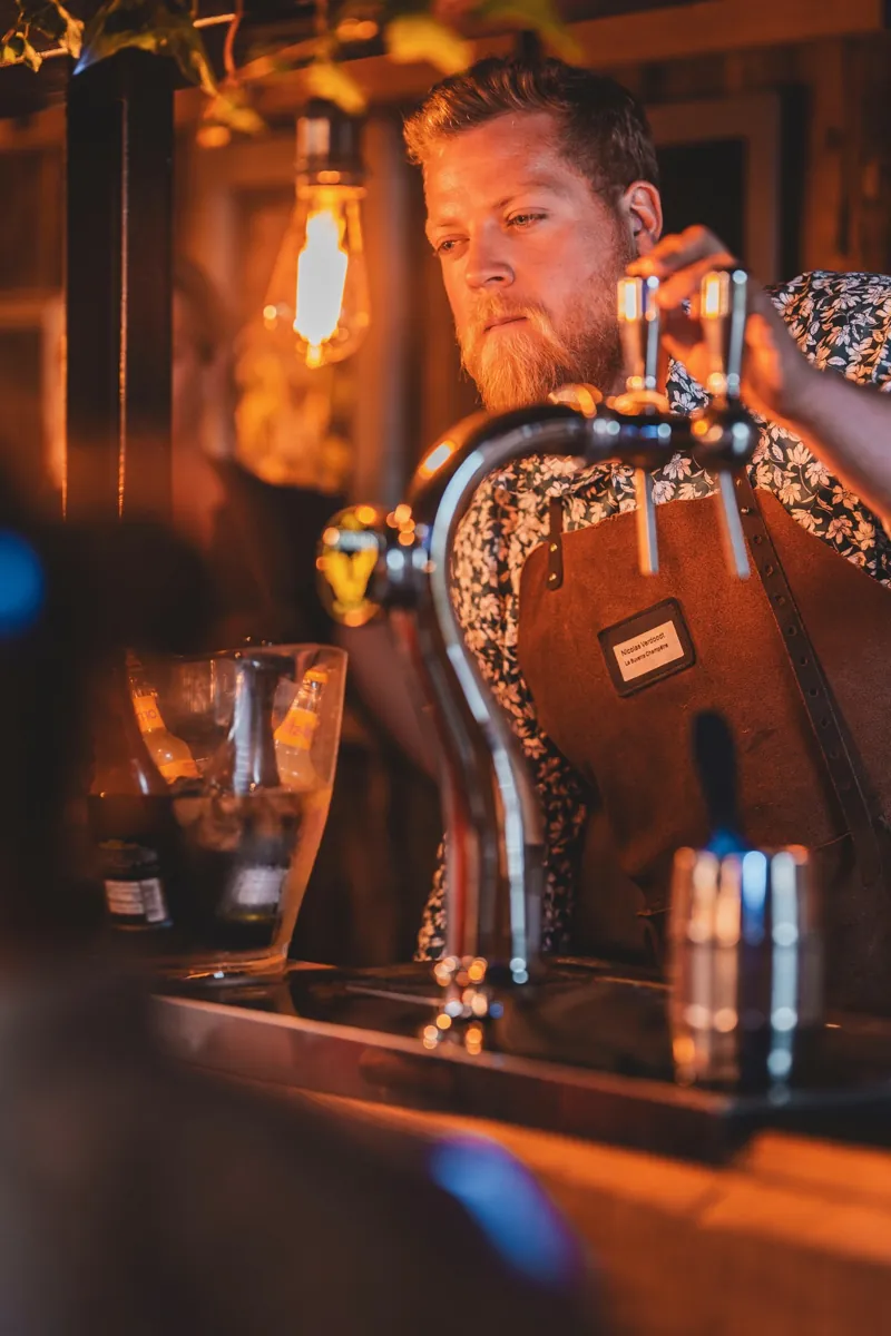 Serveur tirant une bière sous les ampoules de la buvette